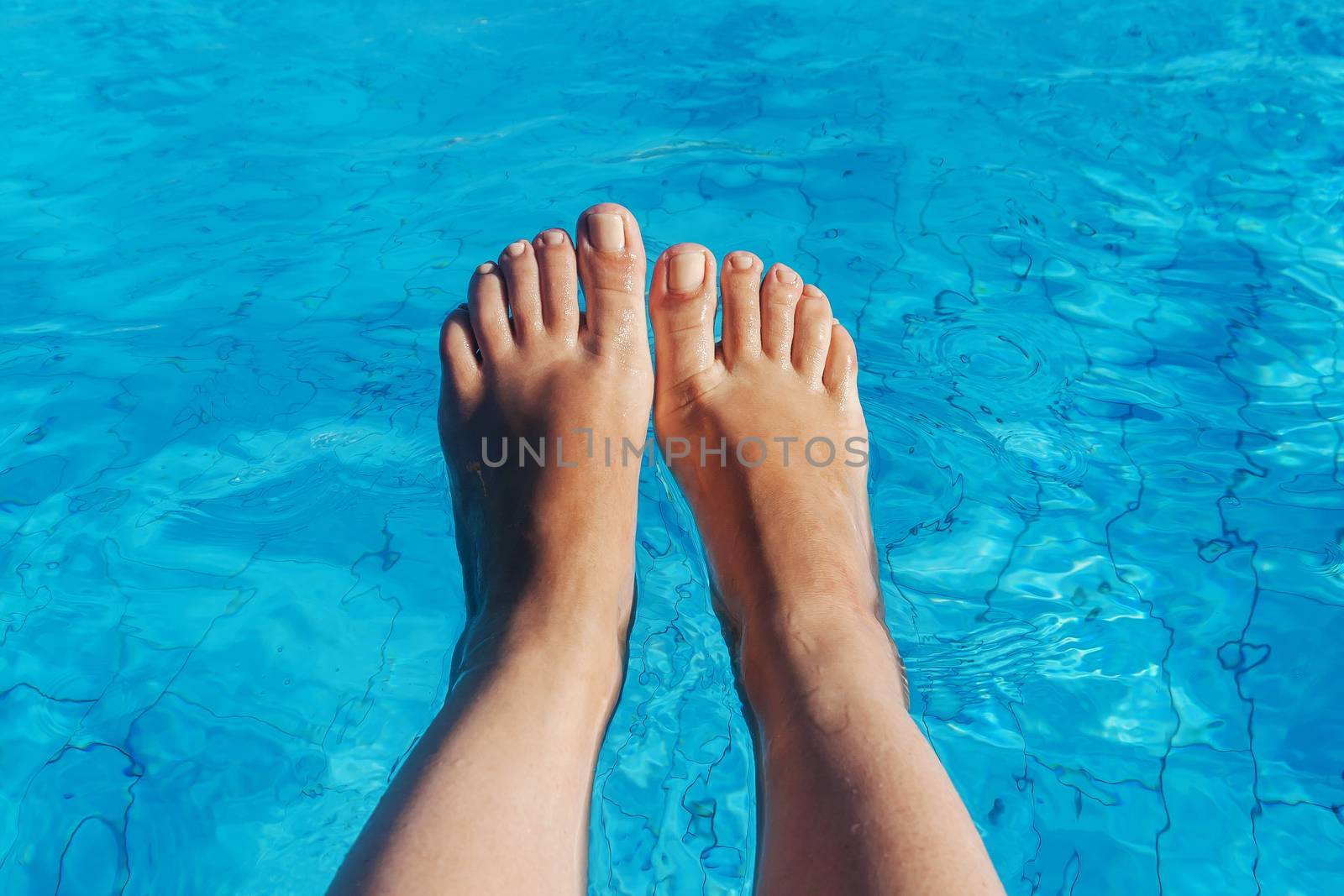 naked female legs on a background of blue water.