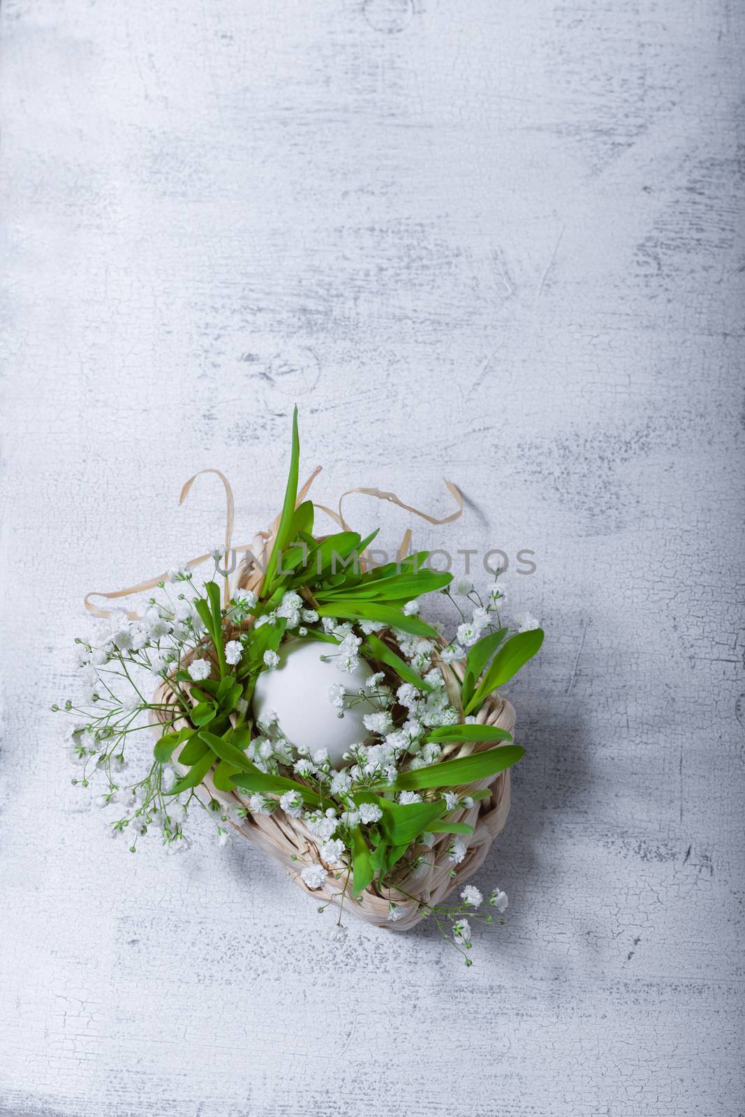 Egg and flowers on a white surface. Easter symbols by supercat67