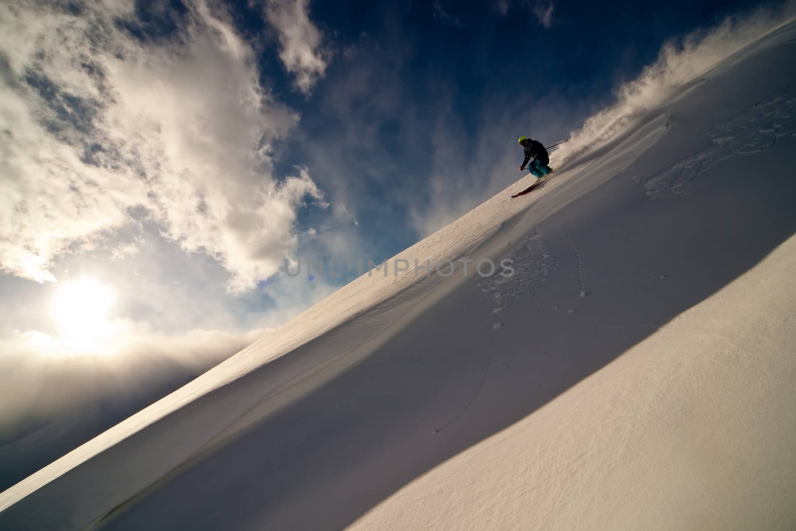 Freerider moving down a slope. Winter sunset in the mountains