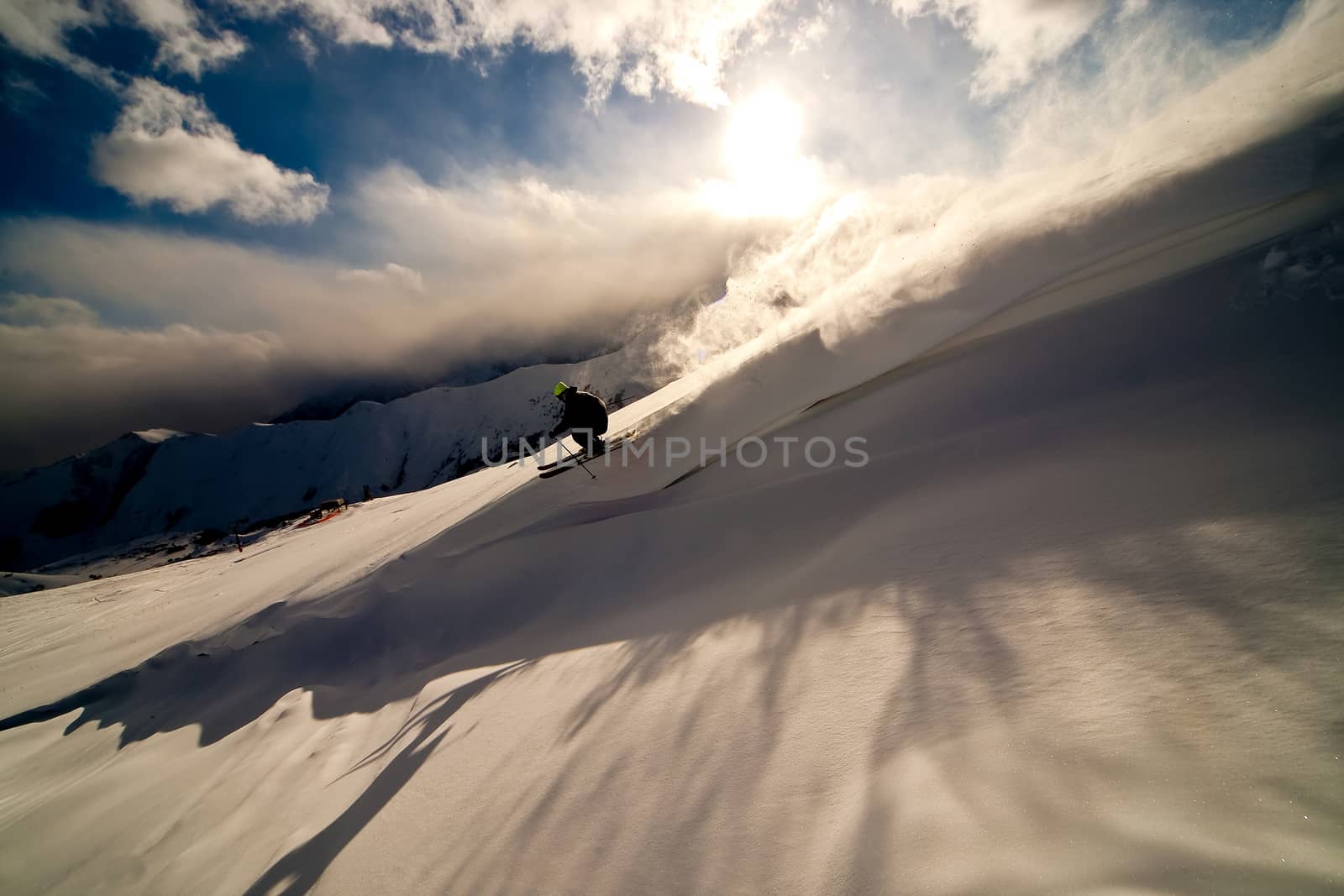 Freerider moving down a slope. Winter sunset in the mountains