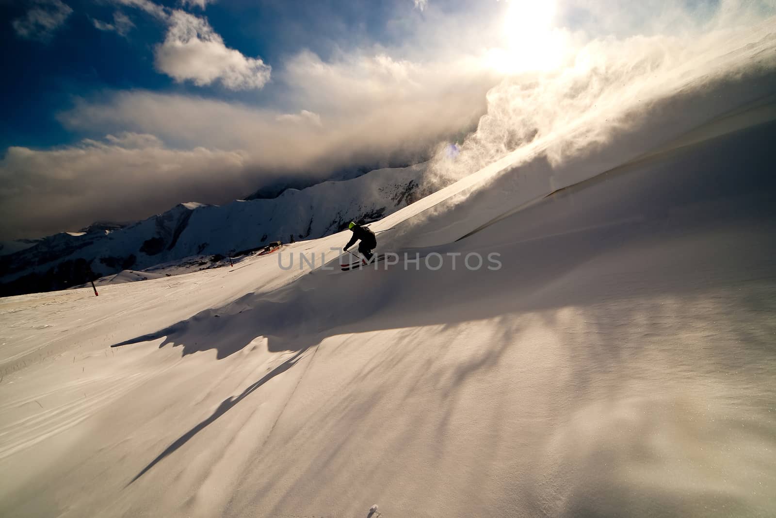 Freerider moving down a slope. Winter sunset in the mountains