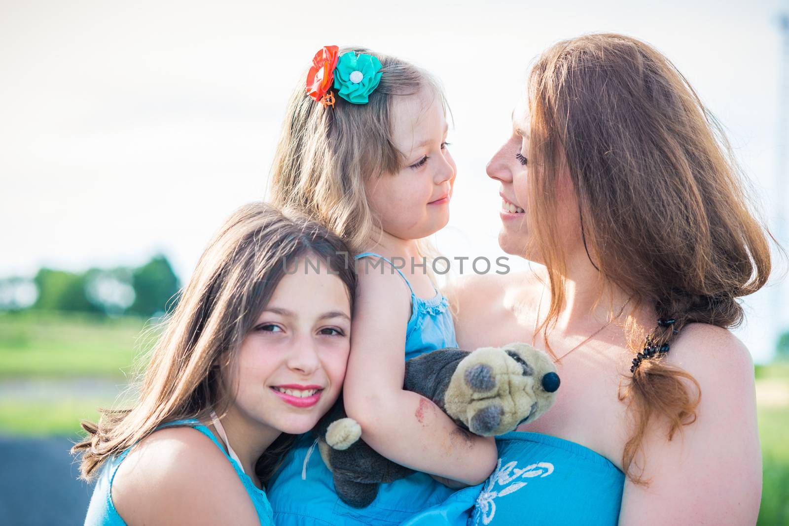 portrait of mother and two daughters. mother looking at daughter