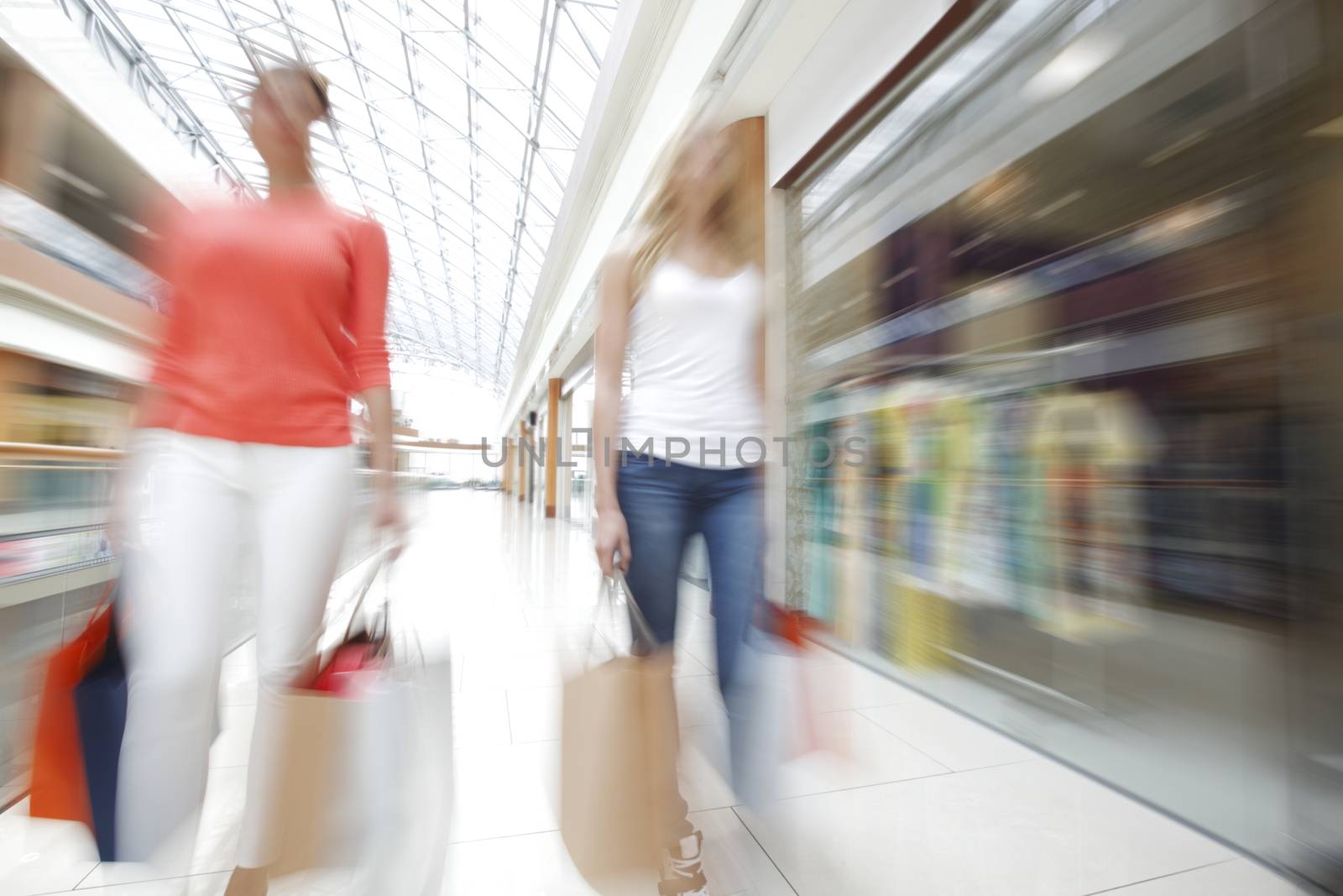 Women walking fast in shopping mall with bags