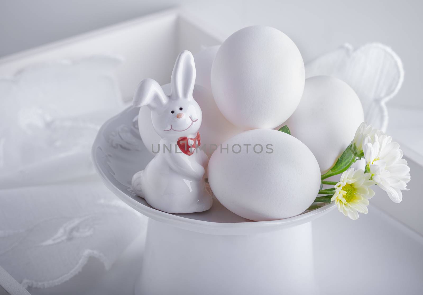 Eggs Rabbit and flowers on white surface. Easter symbols