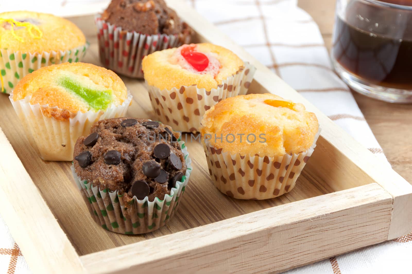 Cupcake various flavors in wood tray on wood table.