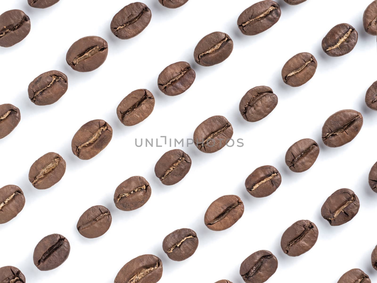 Diagonal rows of coffee beans closeup on white background. Top view or flat lay