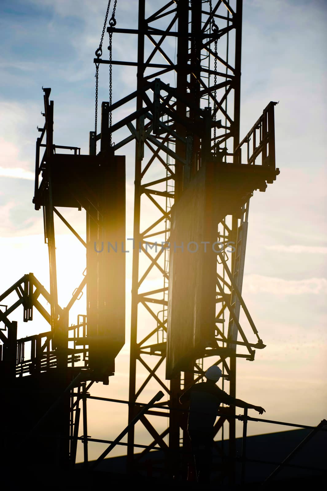 Construction worker, crane and building at sunset, France