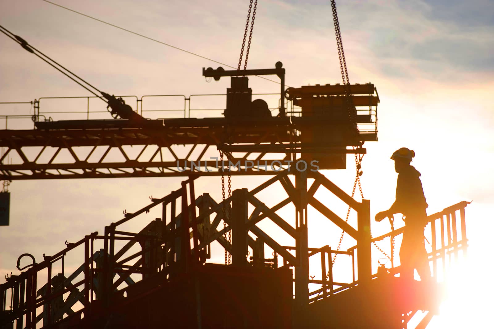 Construction worker, crane and building at sunset, France