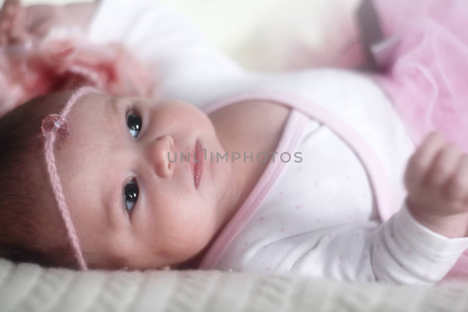 Beautiful smiling newborn baby girl in pink dress on bed