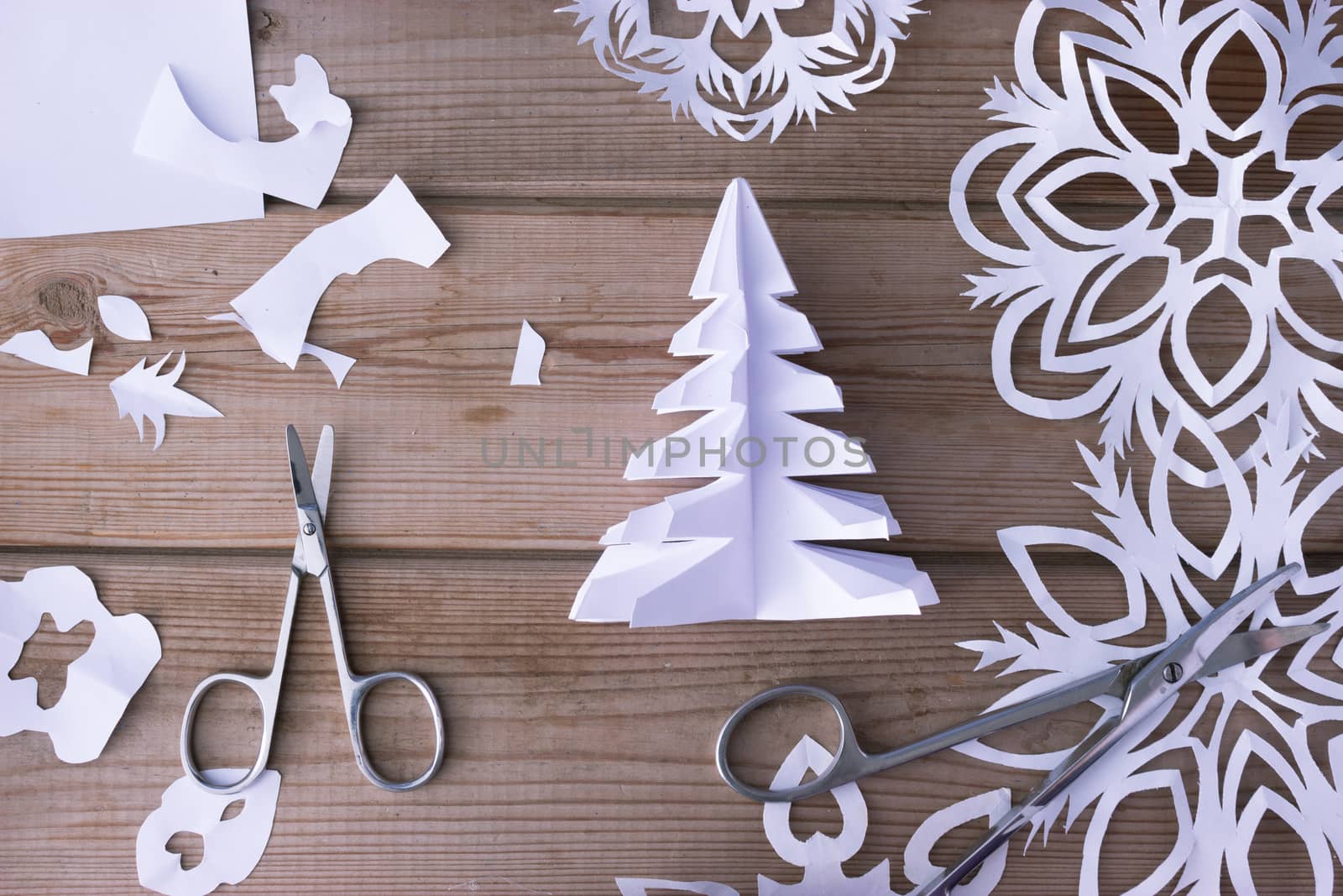 handmade paper snowflakes and scissors on wooden table, background
