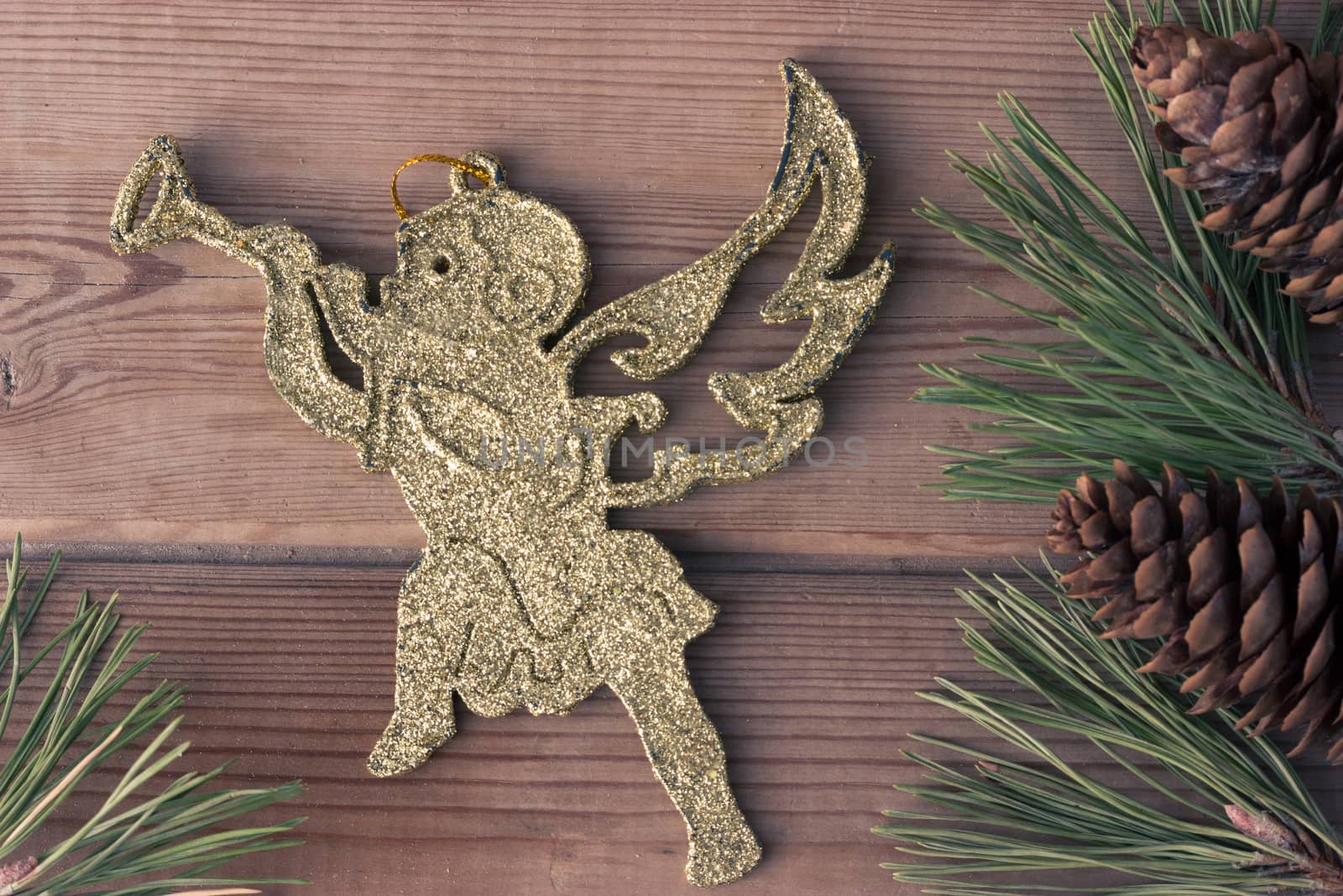 golden Christmas cherub and Christmas tree branches on wooden table