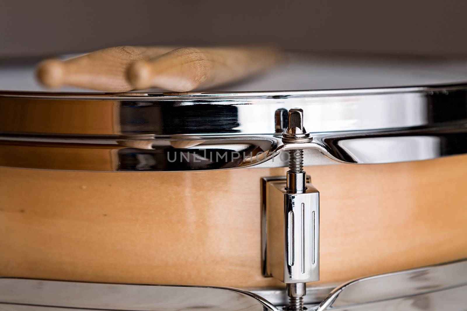 Close up of a wooden snare drum with drumsticks above