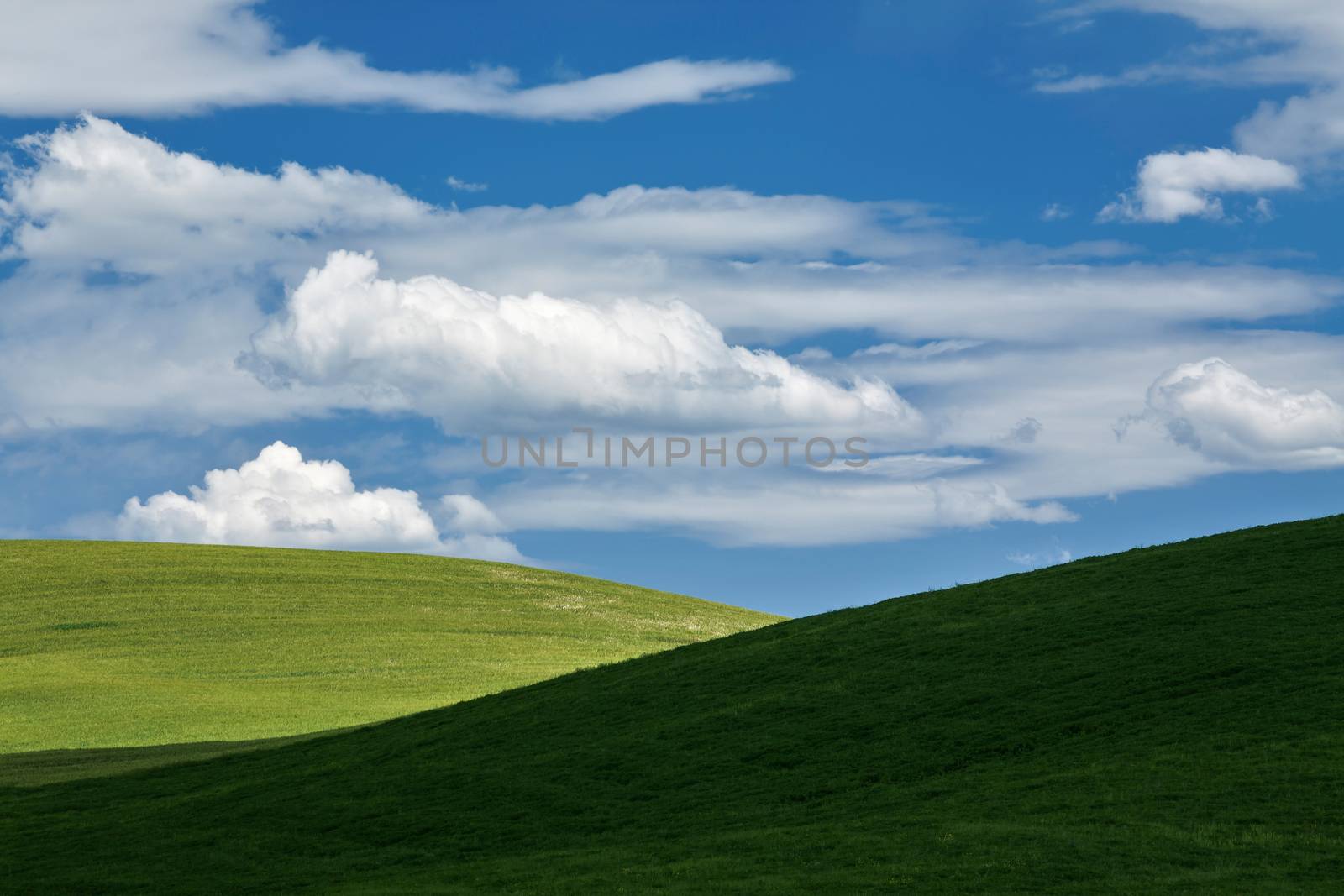 The passage of white clouds above the green hills of the Val d'Orcia in a warm and sunny spring day