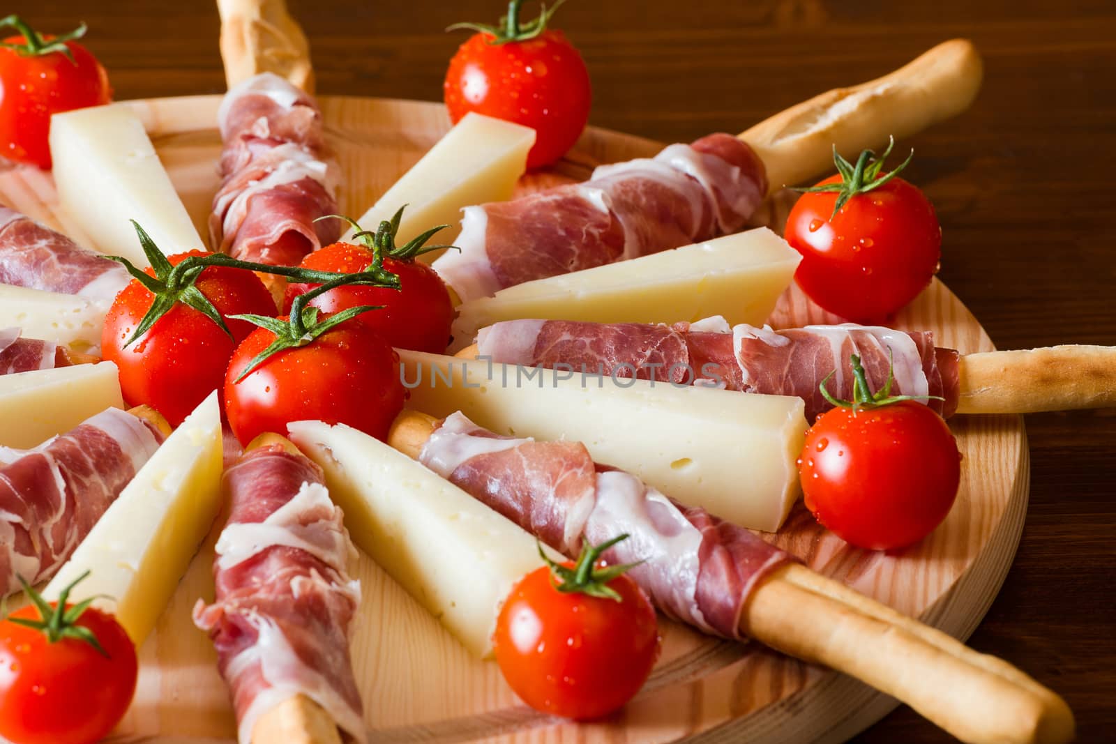 Close up of an Italian chopping board with ham cheese and cherry tomatoes