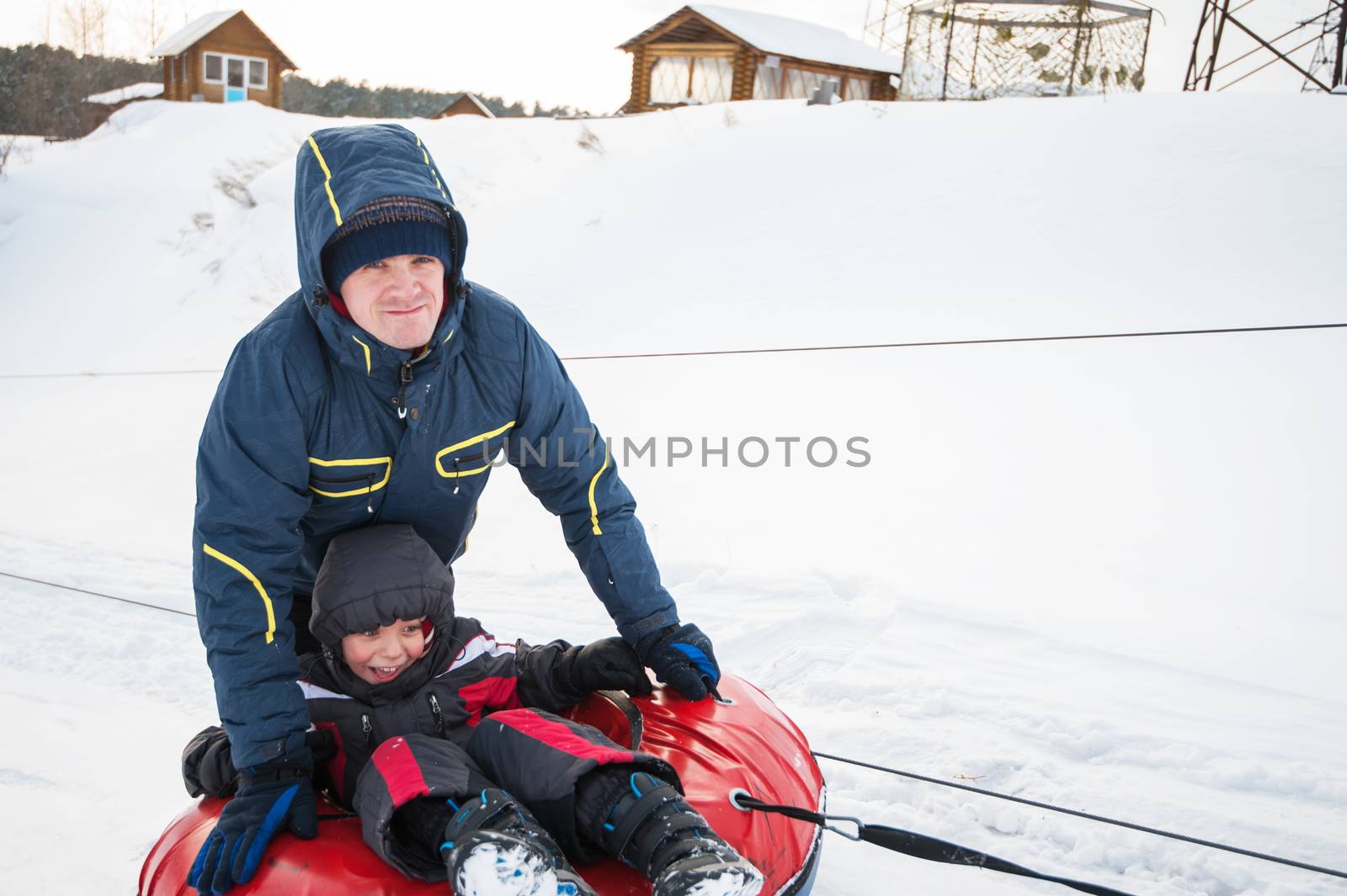 Father and his son having fun on a snow tube, at beauty winter day