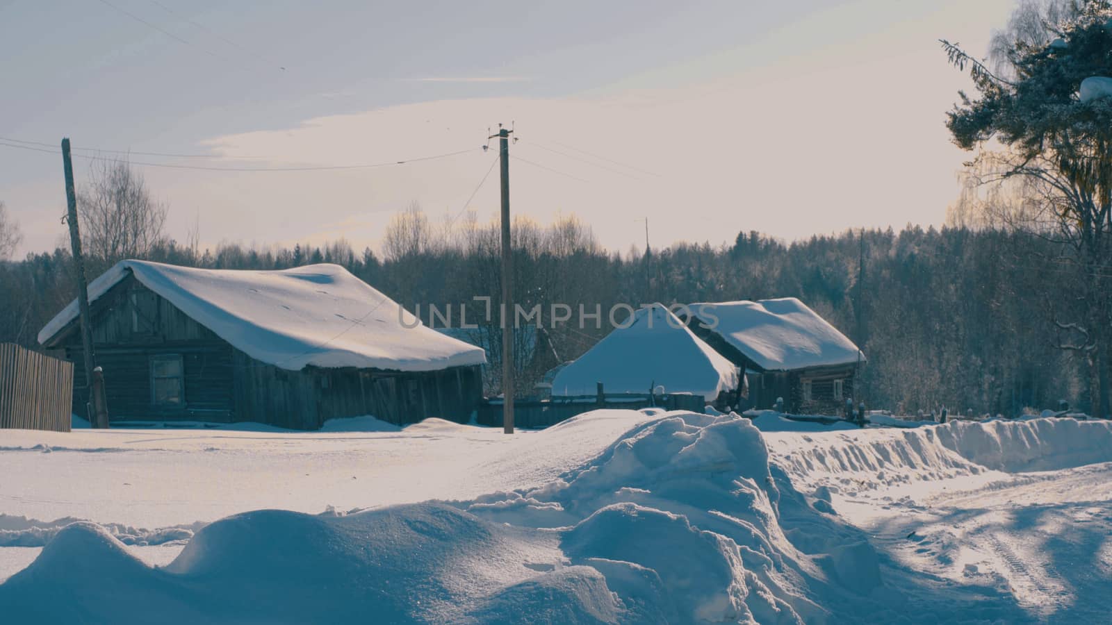 Winter village in a forest. Snow covered roofs of wooden houses, 4K