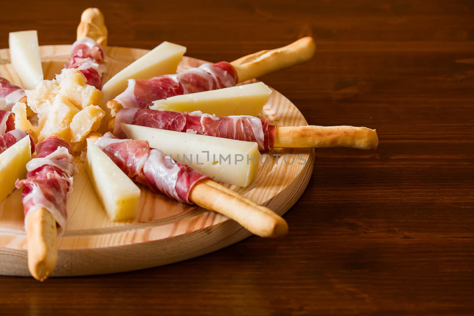 Typical Italian cutting board with ham rolled in bread-sticks and cherry tomatoes