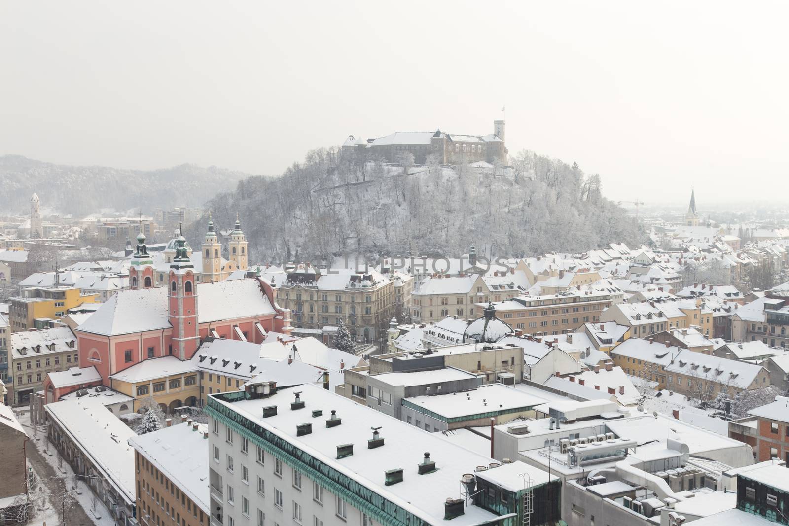 Aerial panoramic view of Ljubljana in winter time. Slovenia, Europe. Rooftops covered in snow.
