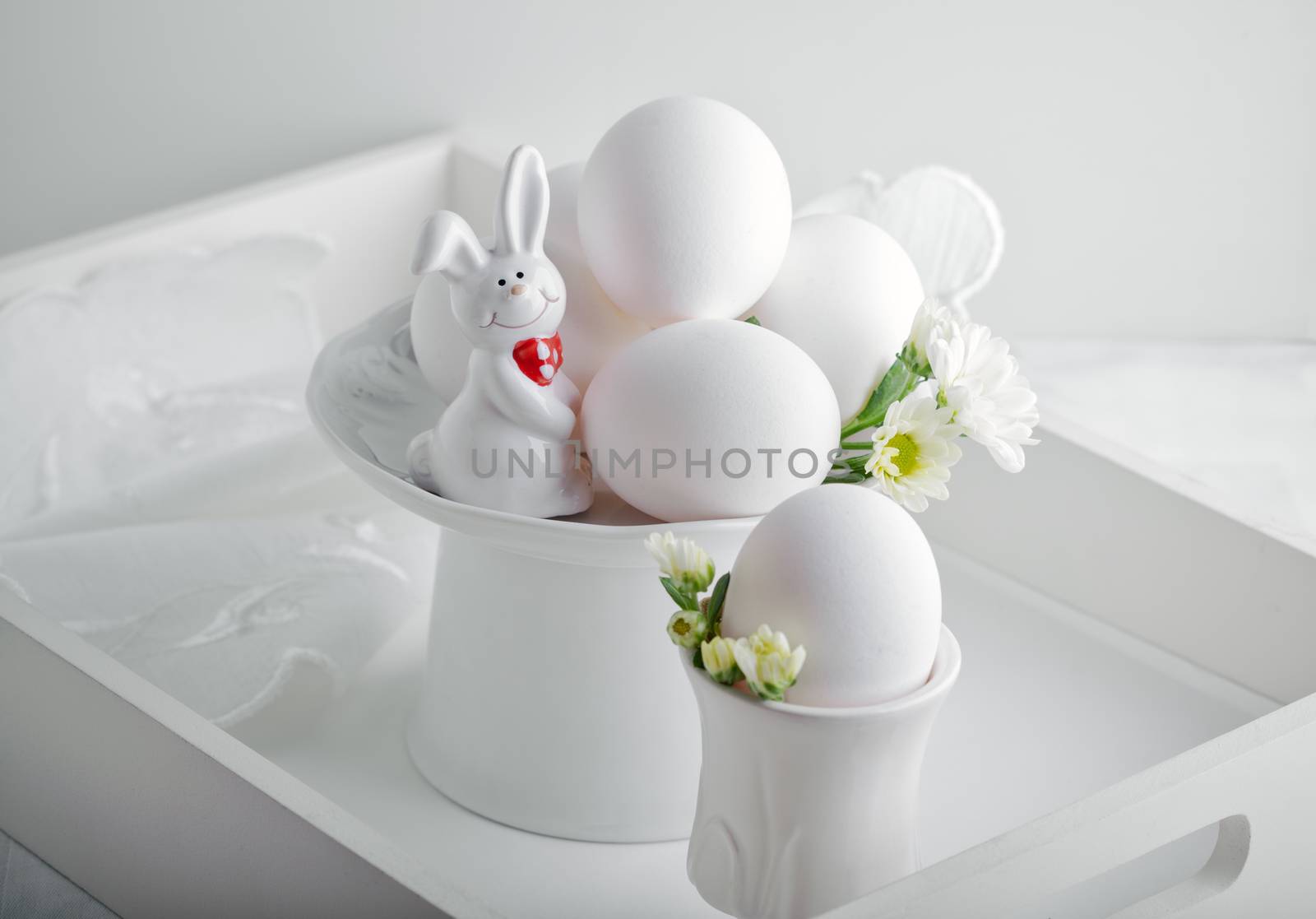 Eggs, rabbit and flowers on a white surface. Easter symbols