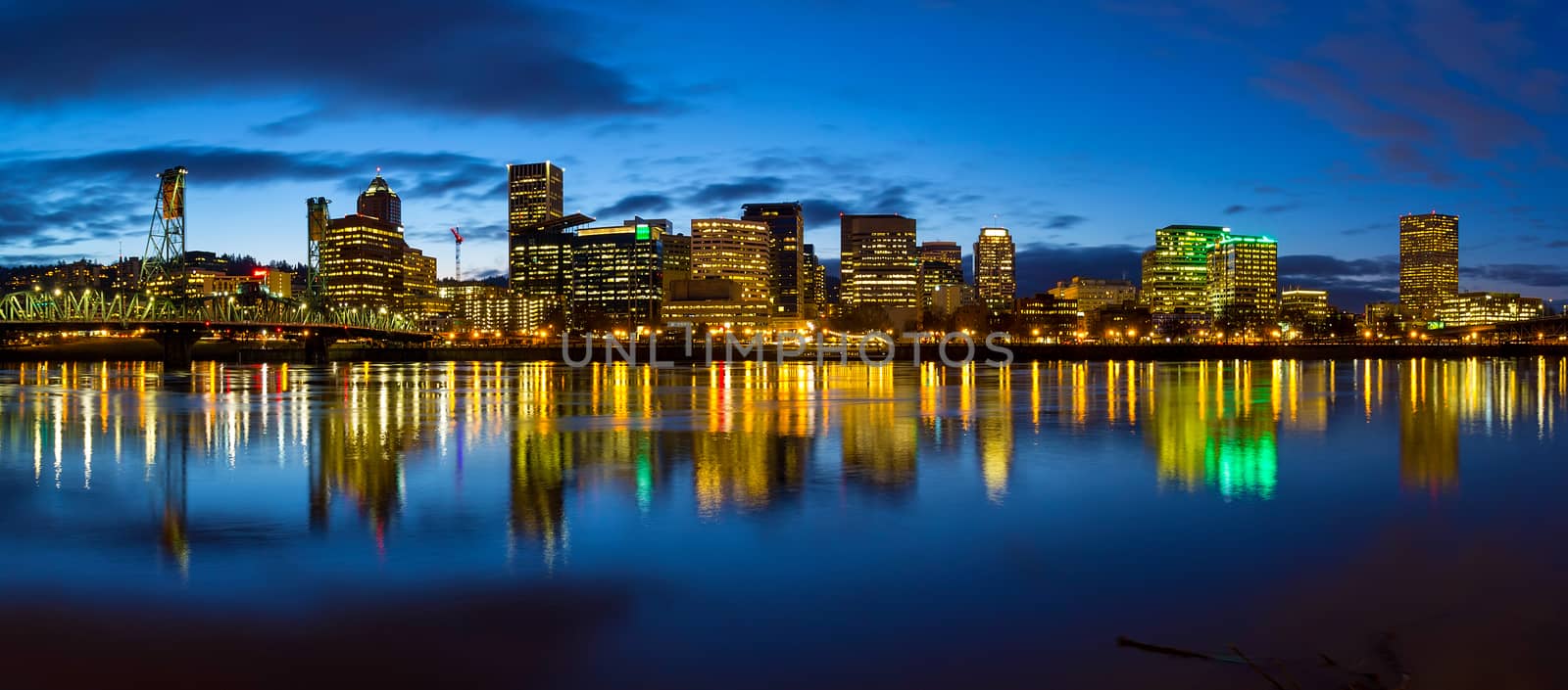 Portland Oregon downtown city skylinw by Hawthorne Bridge along Willamette River at evening blue hour panorama