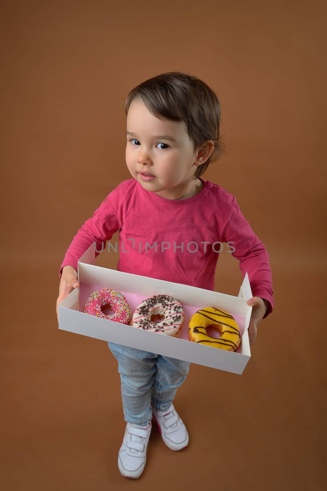 little girl  with different donuts in studio