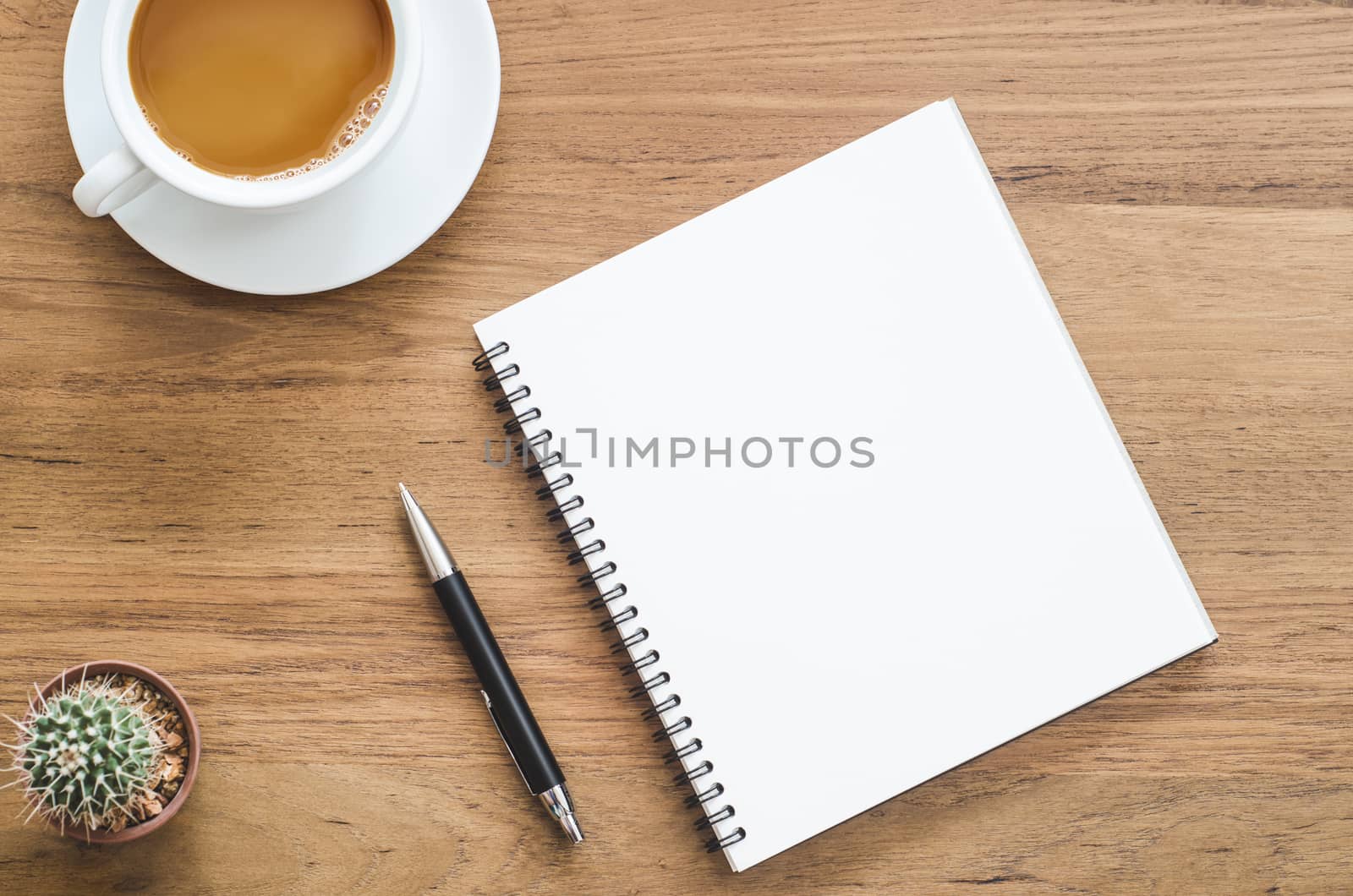 Wooden desk table with notebook, pen, cactus and cup of coffee. Top view with copy space, flat lay.