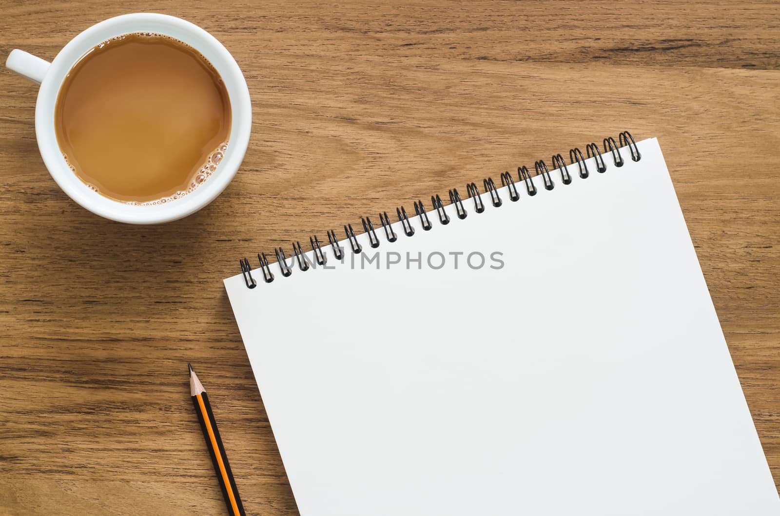 Wooden desk table with notebook, pencil and cup of coffee. Top view with copy space, flat lay.