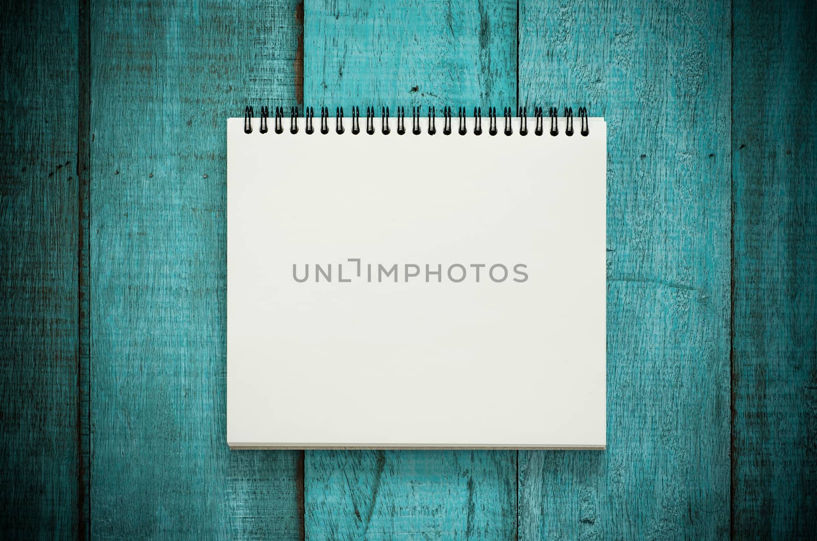 Blue wooden desk table with blank notebook. Top view with copy space, flat lay. Vintage filter