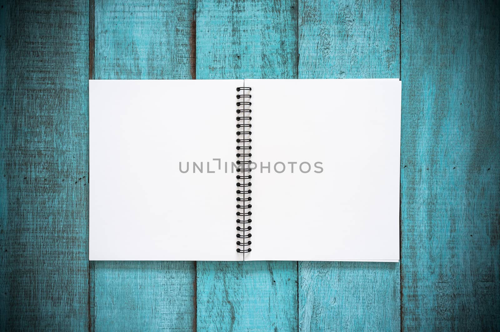 Blue wooden desk table with blank notebook. Top view with copy space, flat lay. Vintage filter