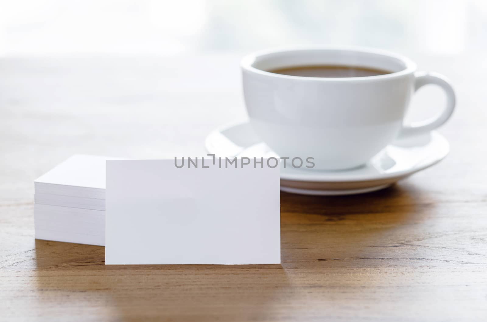 Blank business cards and cup of coffee on wooden table. Corporate stationary branding mock up.