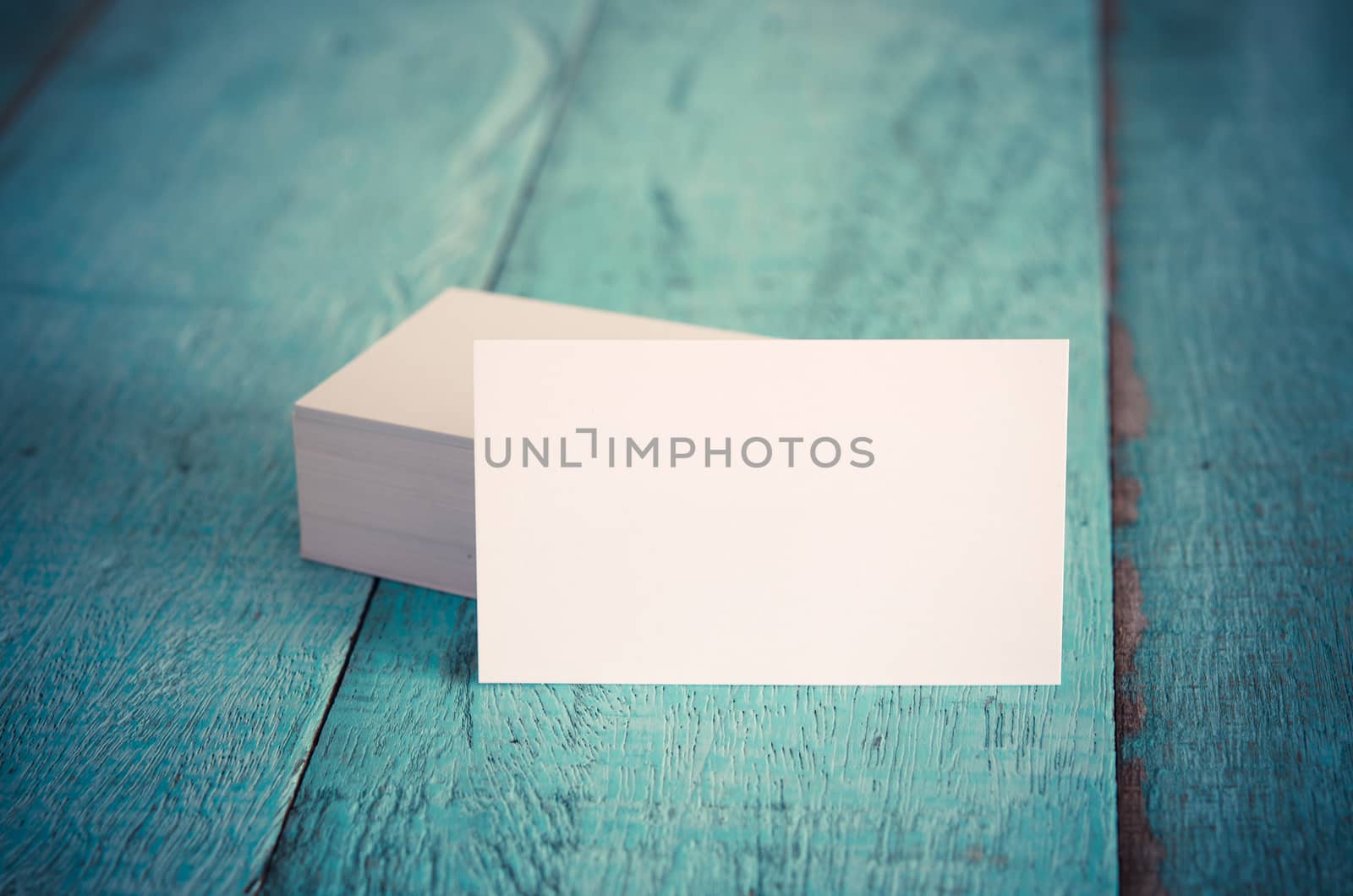 Blank business cards on blue wooden table. Vintage filter.