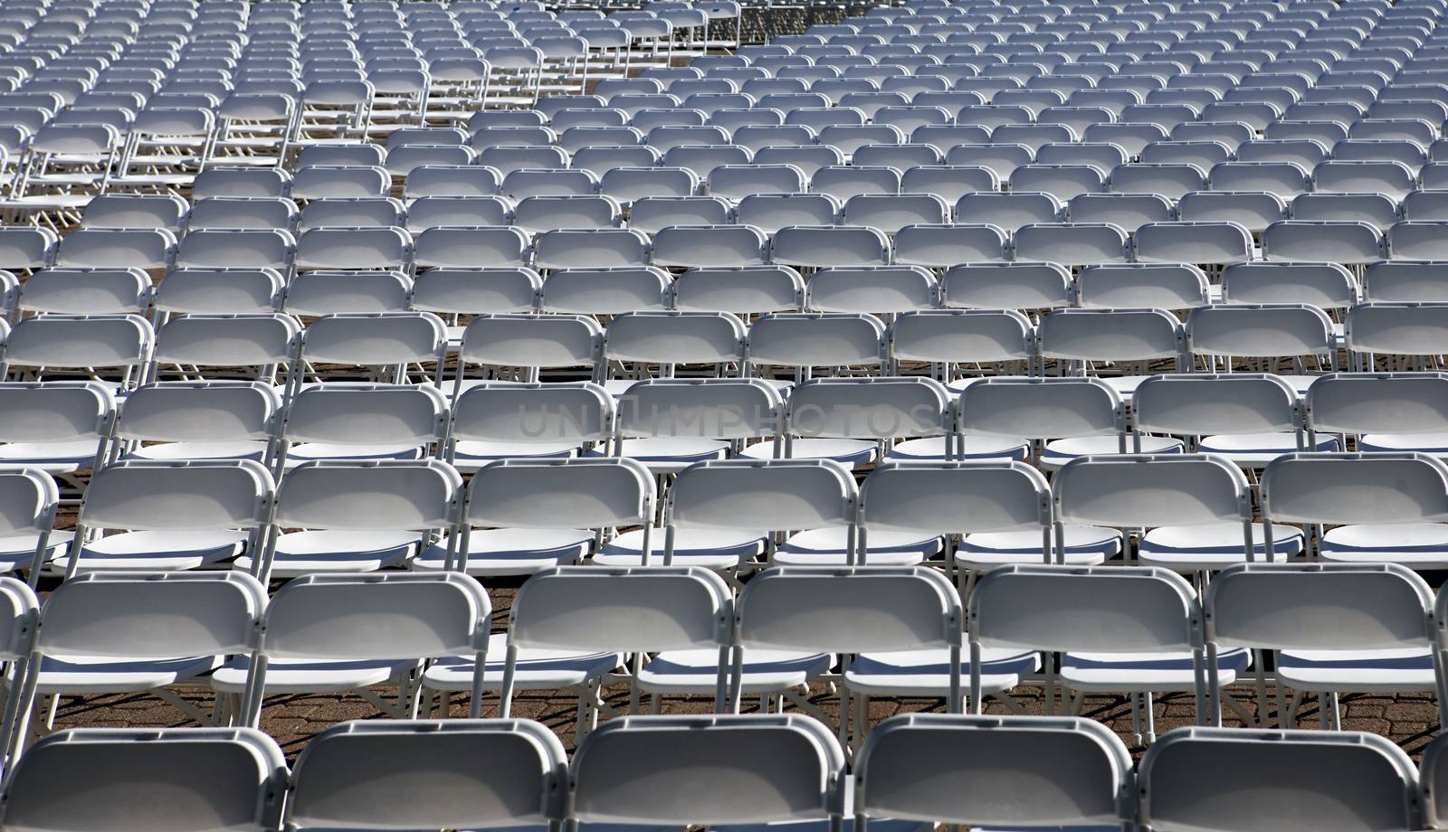 Lots of white chairs at the stadium
