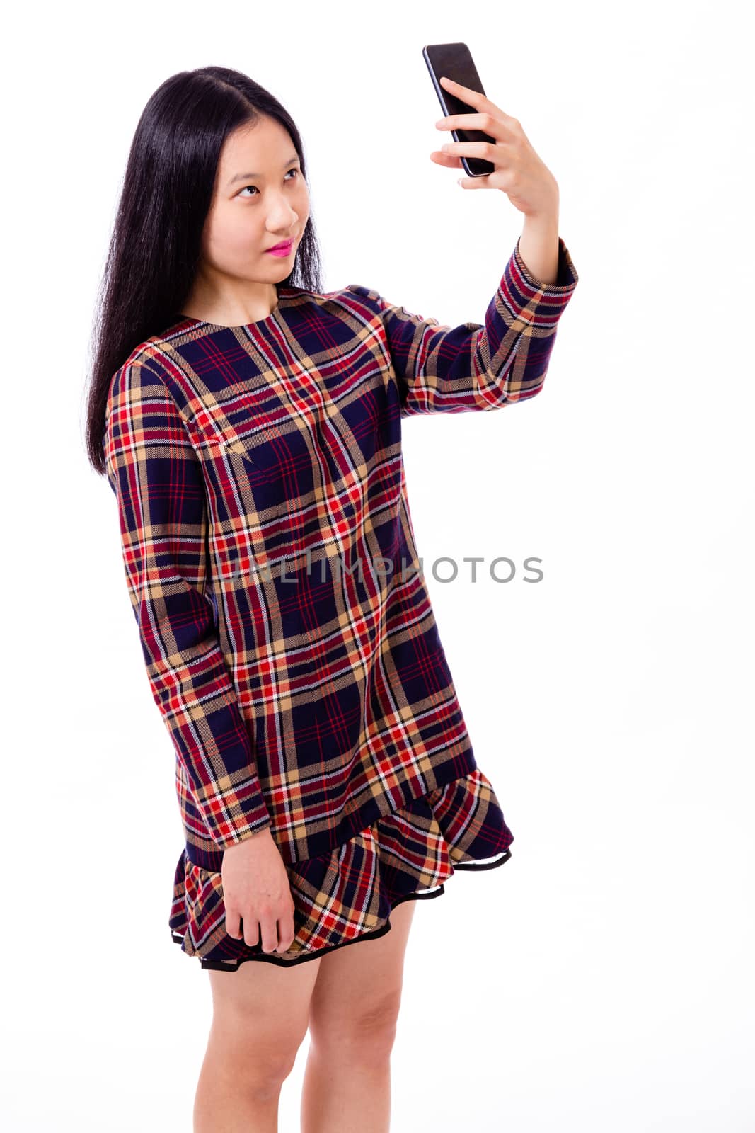 Chinese teenage girl in plaid dress taking selfie with smartphone