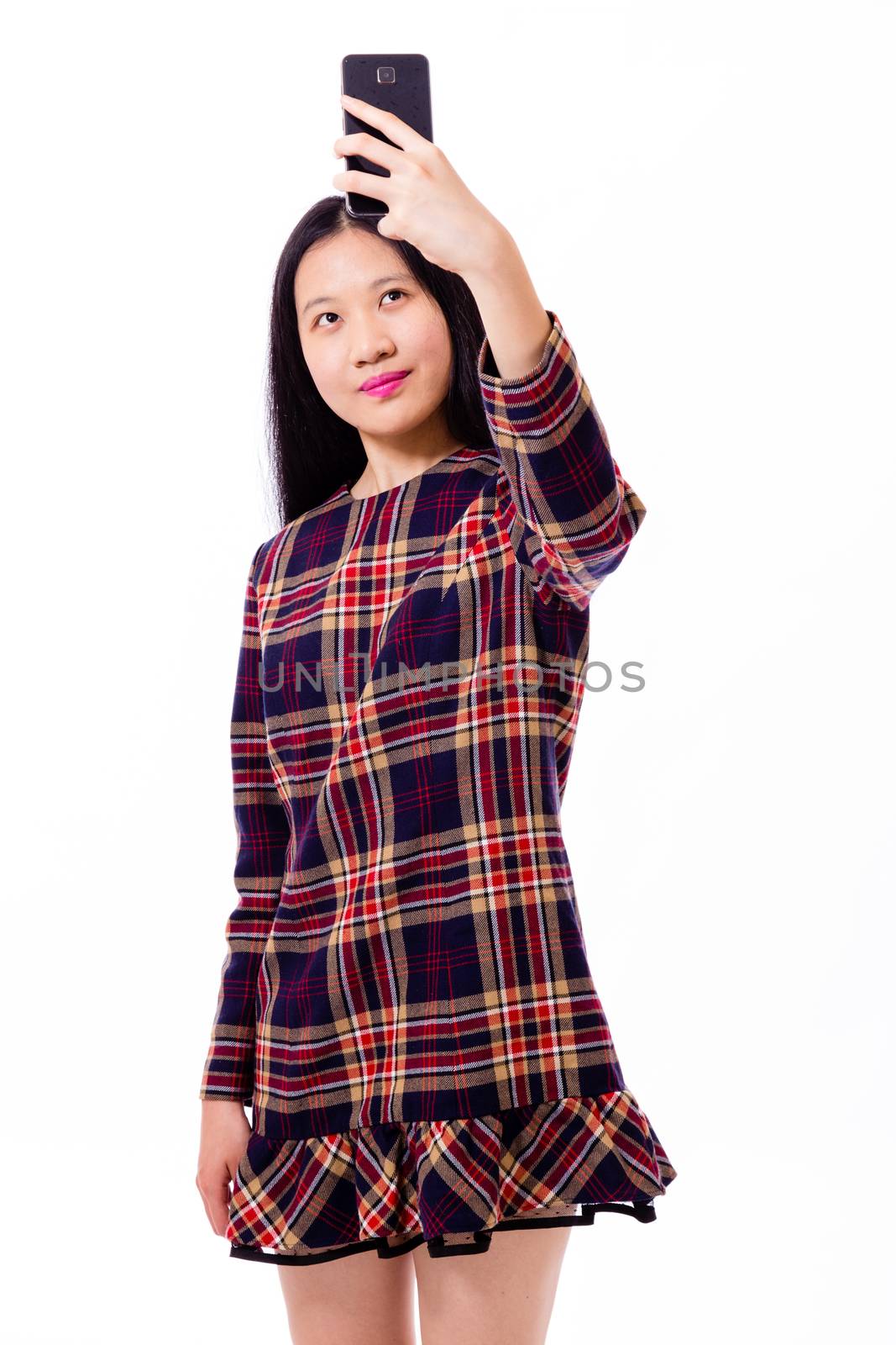 Chinese teenage girl in plaid dress taking selfie with smartphone