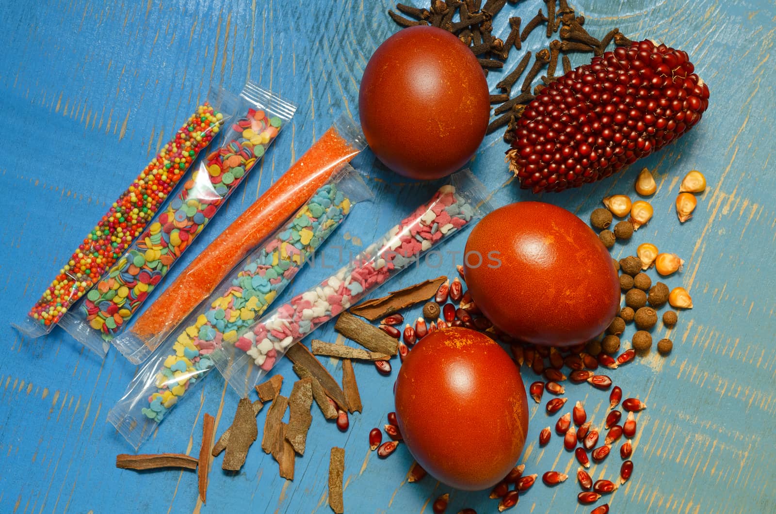 Easter eggs, spices and jewelry for them, on a blue wooden background.