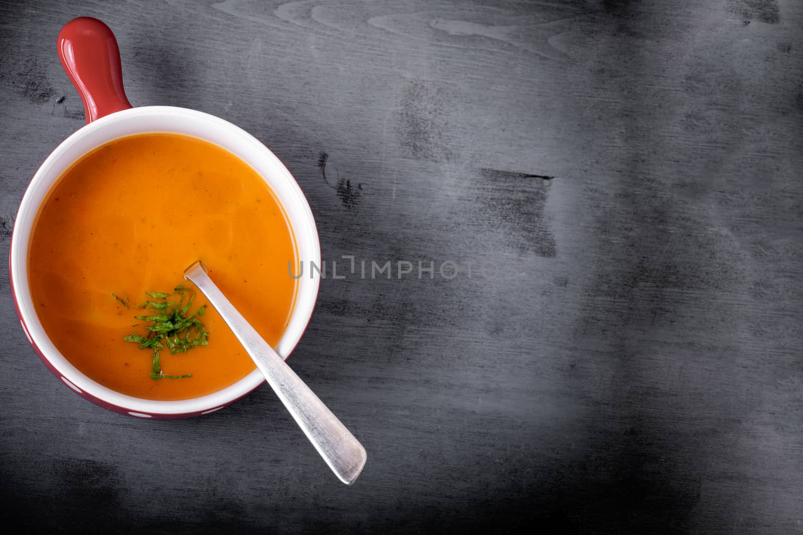 Pumpkin creme soup with a spoon served on a table. by supercat67