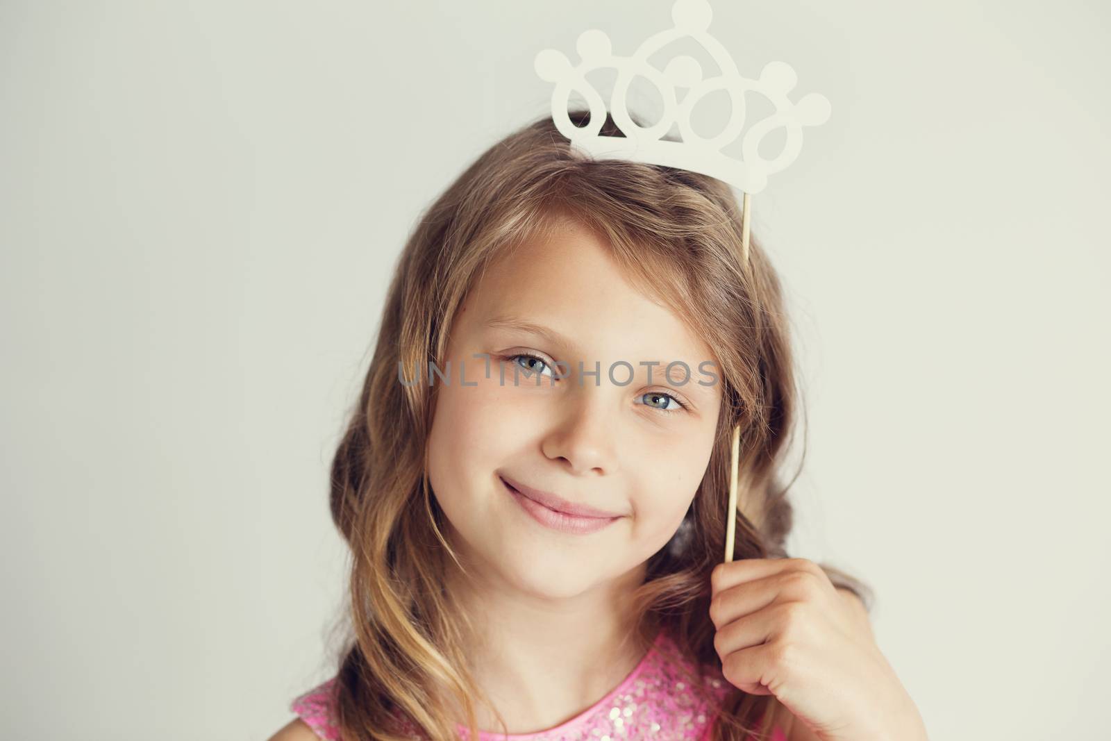 Portrait of a lovely little girl with white paper crown against a white background