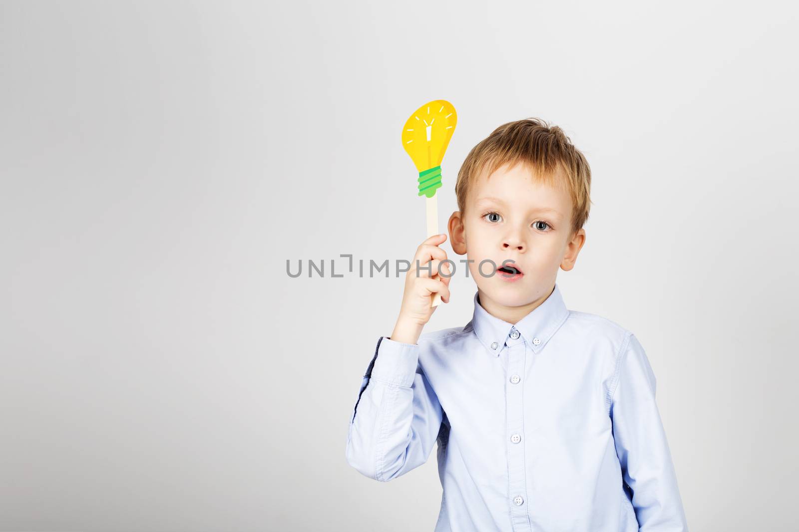 Cute boy with yellow paper lightbulb against a white background. by natazhekova