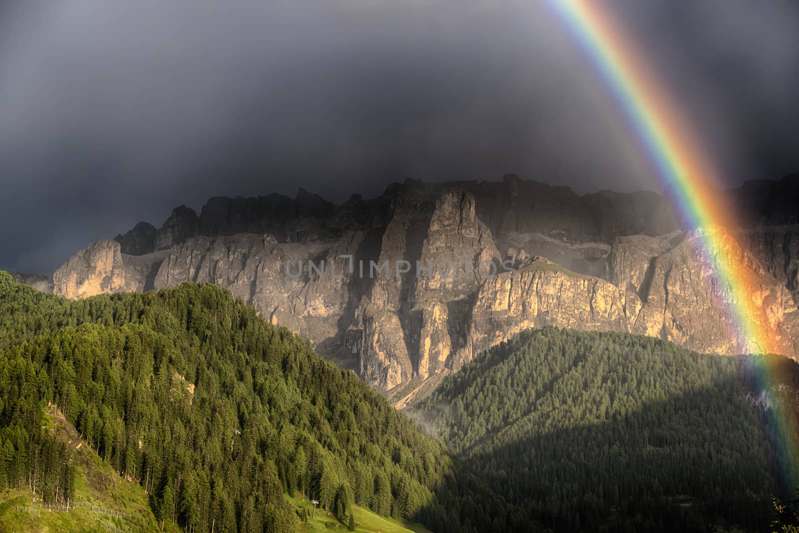 Rainbow after the thunderstorm over the hills and mountains of Selva di Val Gardena in a summer end of the day, Trentino-Alto Adige - Italy