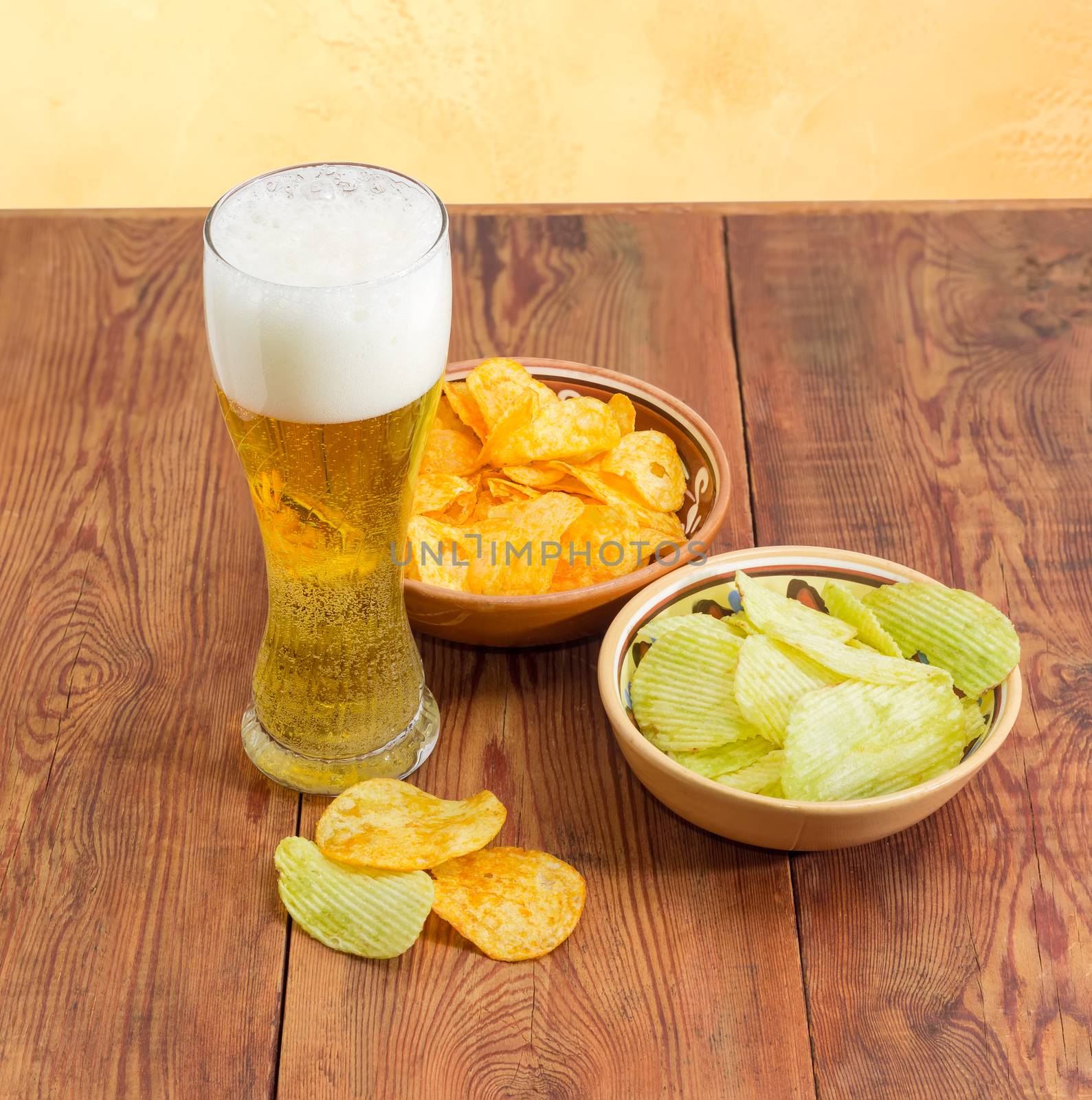 Lager beer and two various potato chips on wooden surface by anmbph