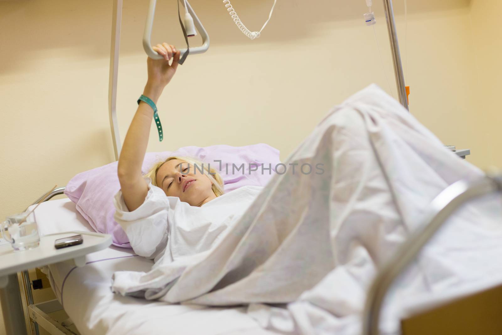 Bedridden female patient lying in hospital bed, recovering after surgery.