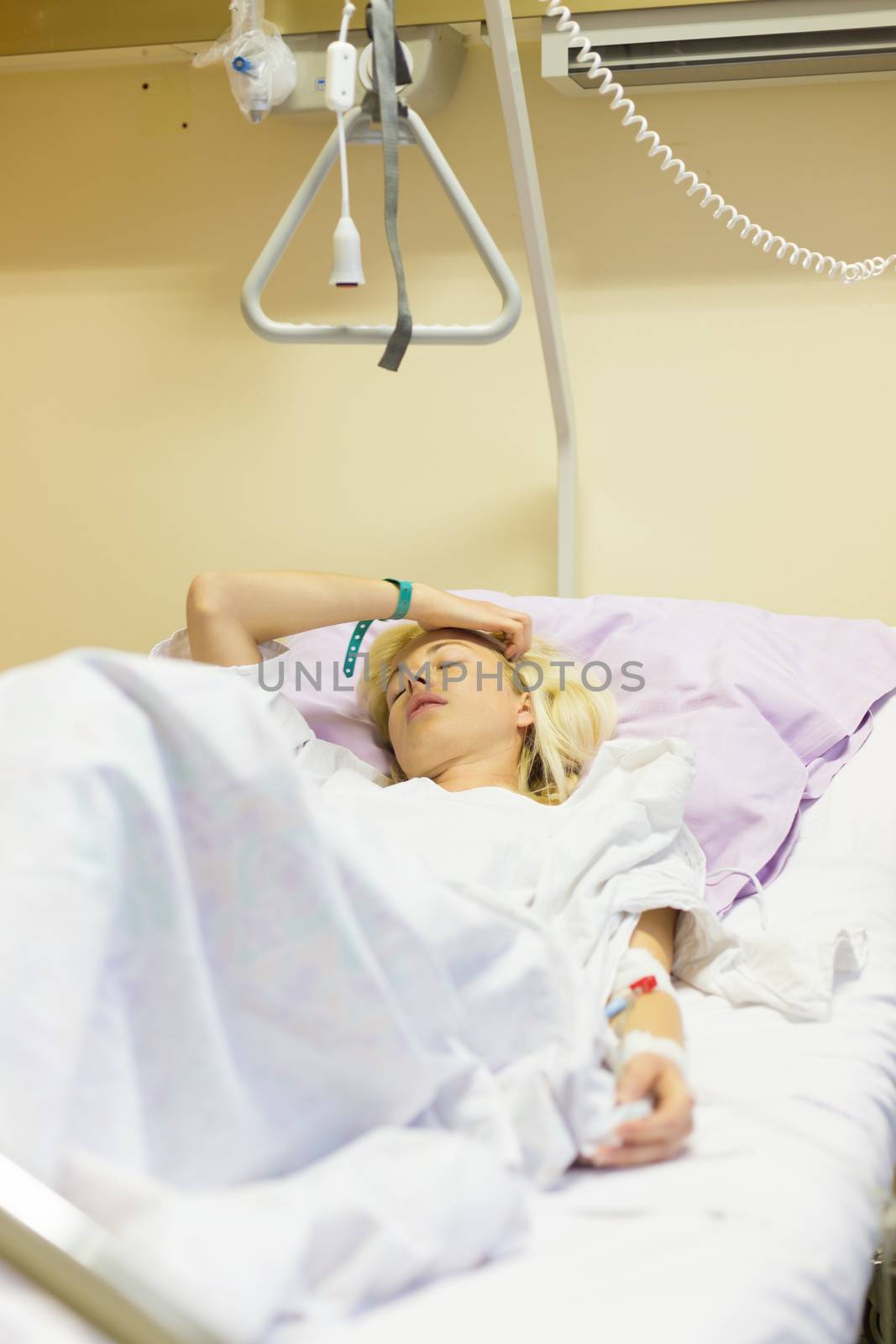 Bedridden female patient lying in hospital bed, recovering after surgery.