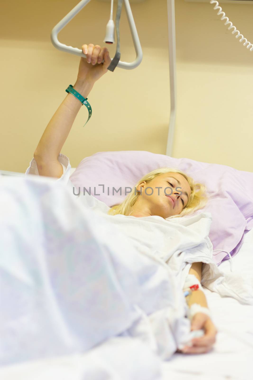 Bedridden female patient lying in hospital bed, recovering after surgery.