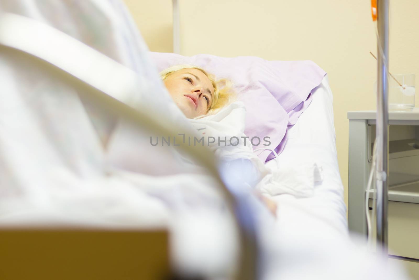 Bedridden female patient lying in hospital bed, recovering after surgery.