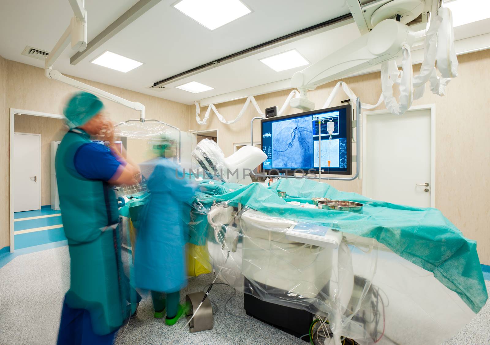 Blurred figures of surgeons during laparoscopic heart surgery in modern hospital.