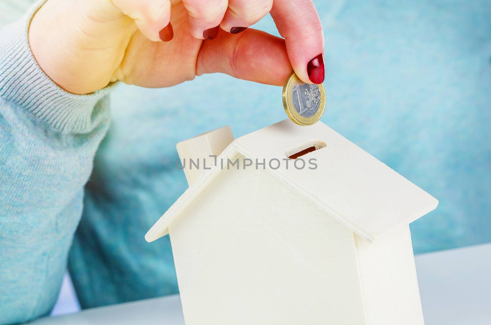 Woman inserting a euro coin into a wooden money box