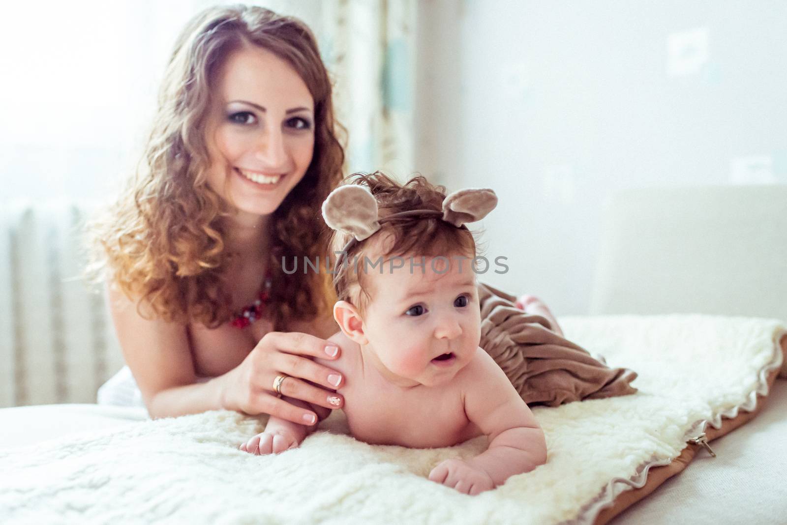 naked baby with mother lying on a white soft blanket