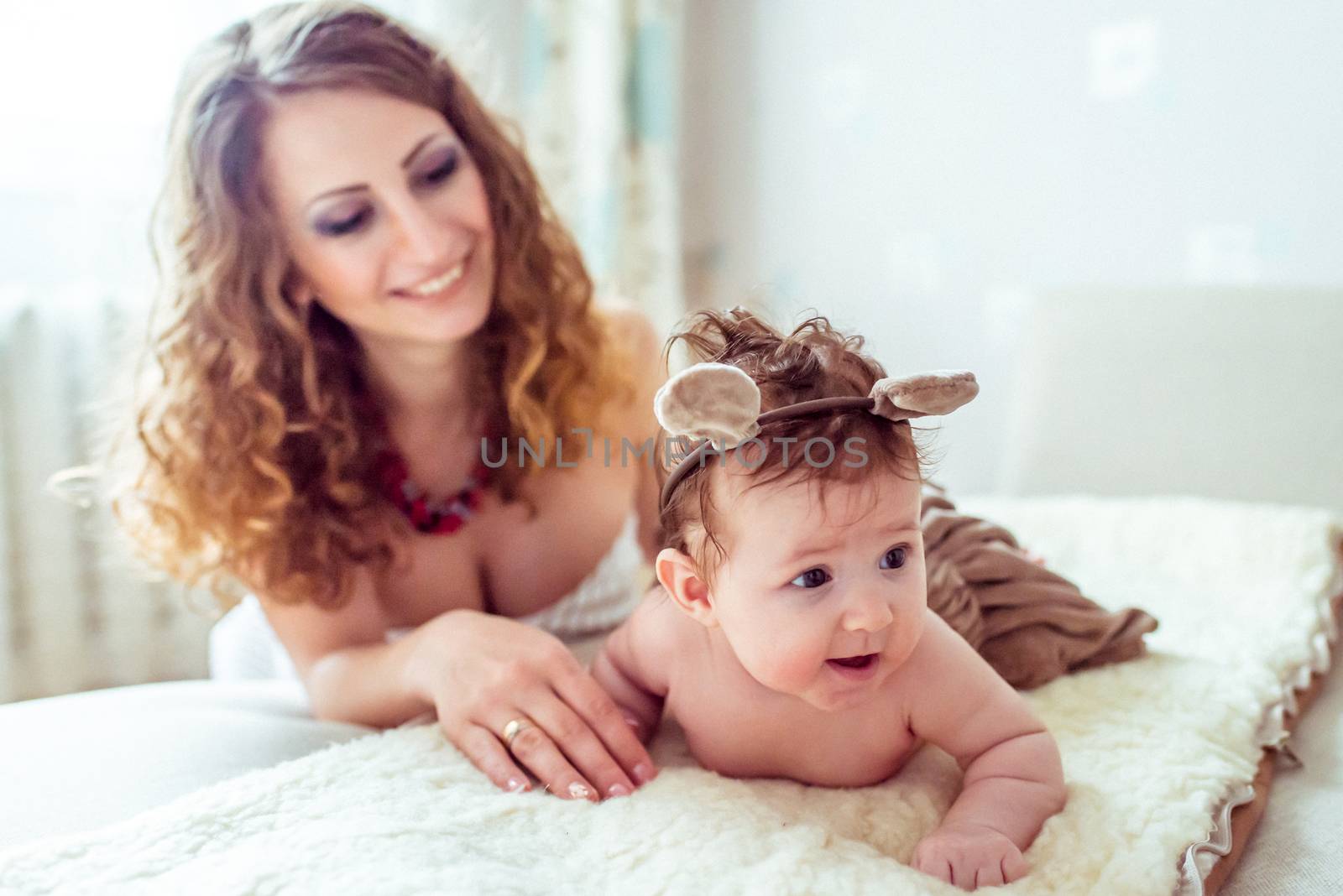 naked baby with mother lying on a white soft blanket