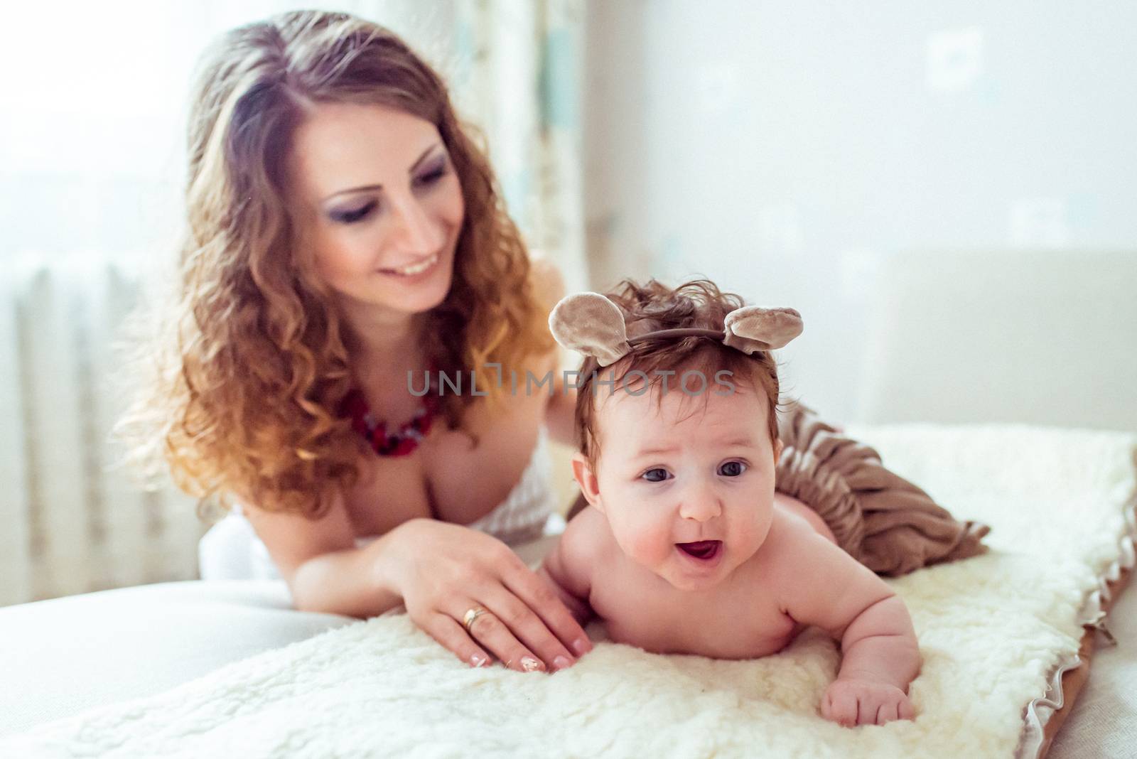 naked baby with mother lying on a white soft blanket