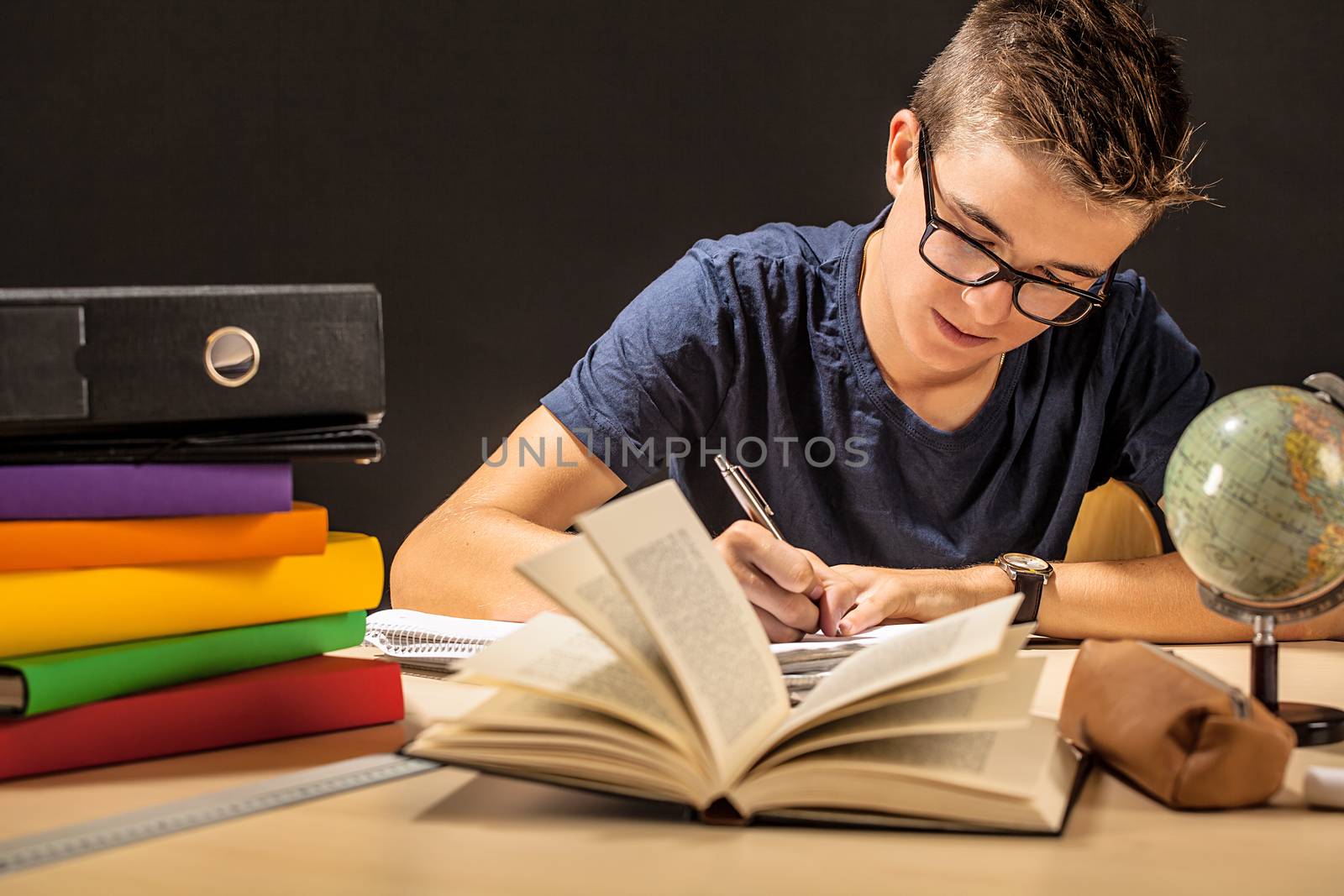 Photo of a male student doing his homework in a dark room.